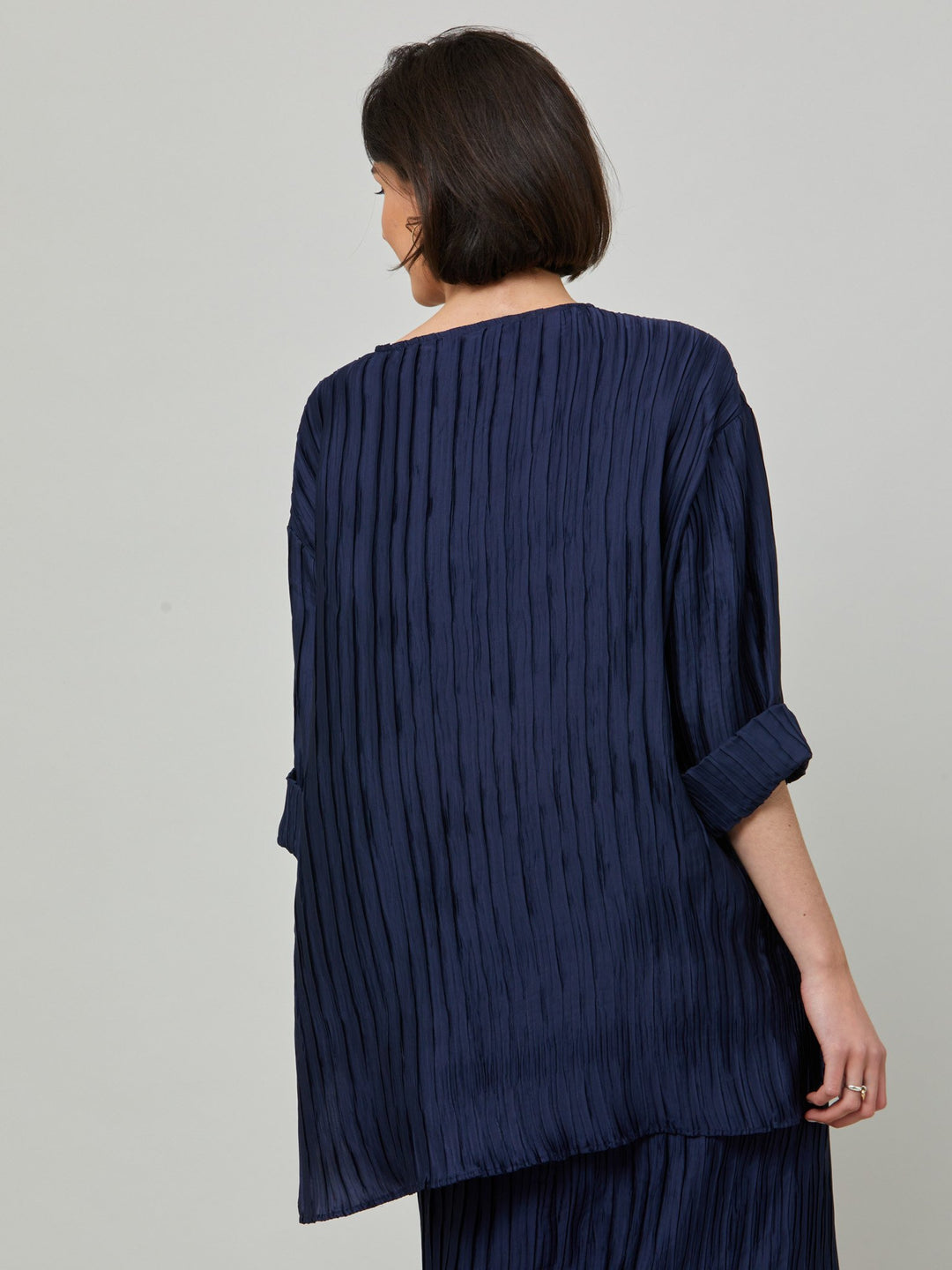 Hallie, elegant tunic in polished navy pleated fabric. A simple wardrobe essential, the perfect foil for the matching Roz navy pleated skirt. Features full-length sleeve, shown here rolled up.