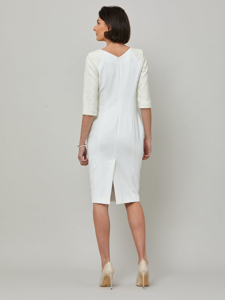back picture of model wearing Juliet, A form-flattering, body-skimming silhouette in iconic white. Features a 3/4 sleeve with lace overlay. The skirt falls to a demure finish below the knee. Attending a summer wedding? Mother of the bride? Heading to the races? This is the dress for you.