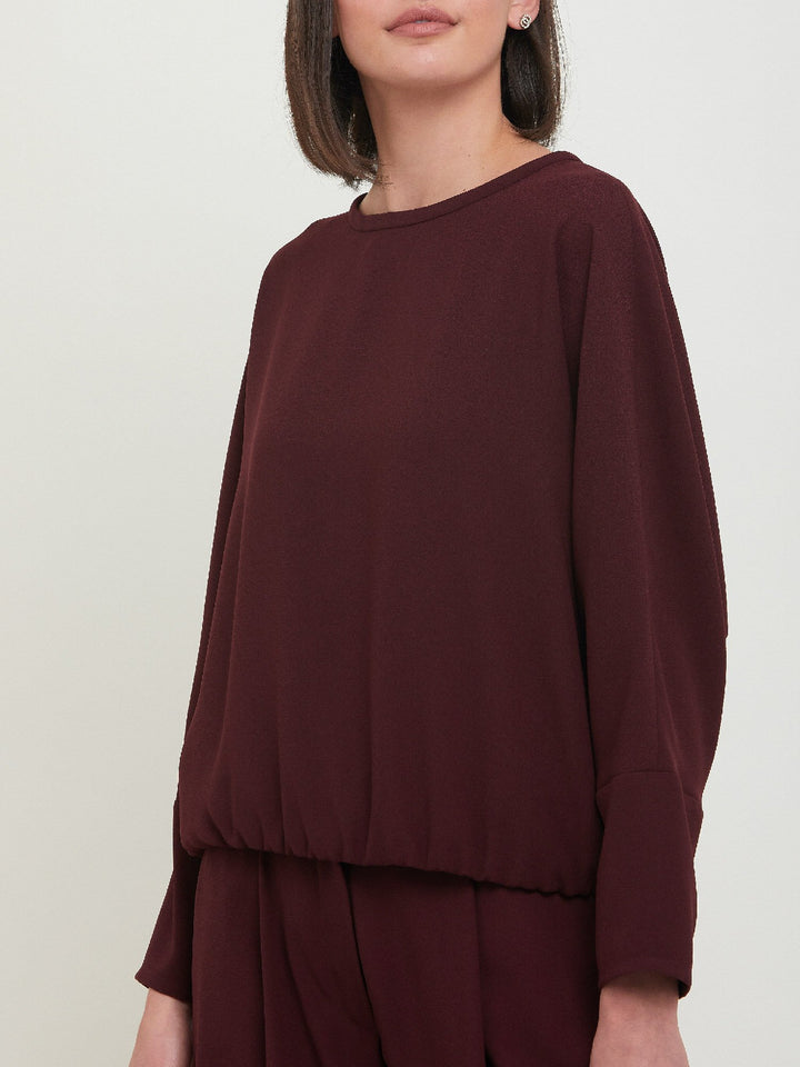Lal, a crewneck relaxed fit sweatshirt. Crafted in a satin back crepe in rich burgundy. A sporty silhouette featuring an elasticated ribbed hem, dropped shoulder & full-length sleeve. Teams perfectly with matching Charlize pants. Clothes for how we live today! Loungewear re-defined. 