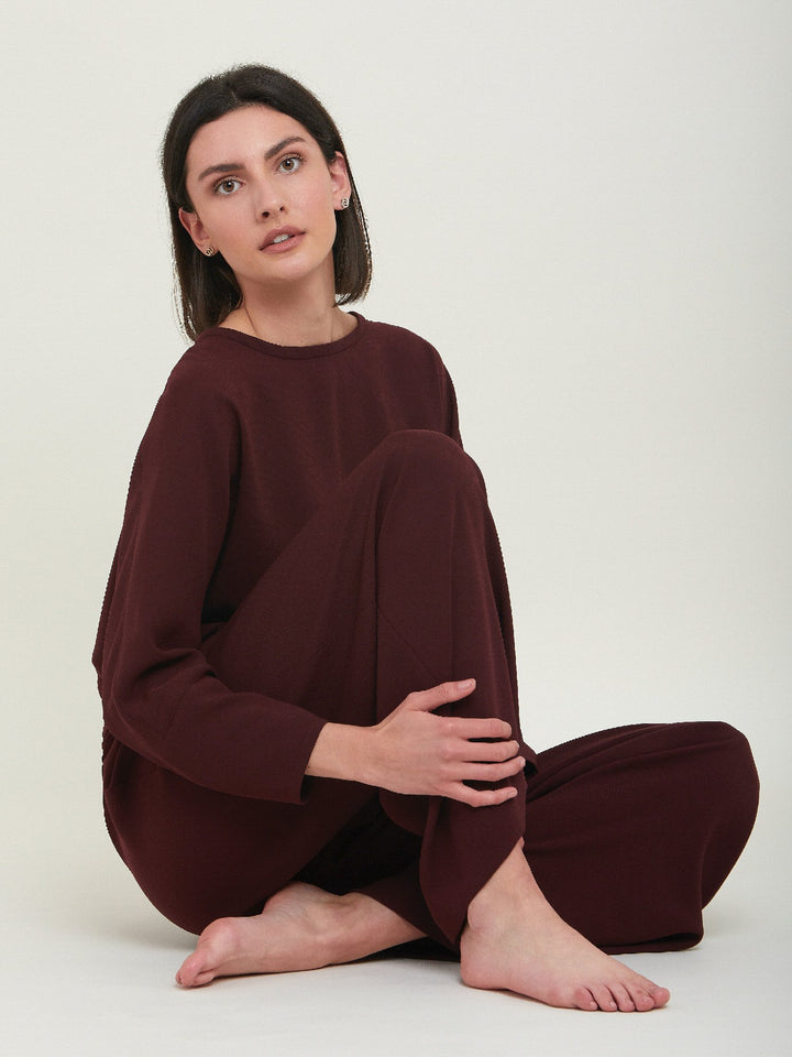 Lal, a crewneck relaxed fit sweatshirt. Crafted in a satin back crepe in rich burgundy. A sporty silhouette featuring an elasticated ribbed hem, dropped shoulder & full-length sleeve. Teams perfectly with matching Charlize pants. Clothes for how we live today! Loungewear re-defined. 