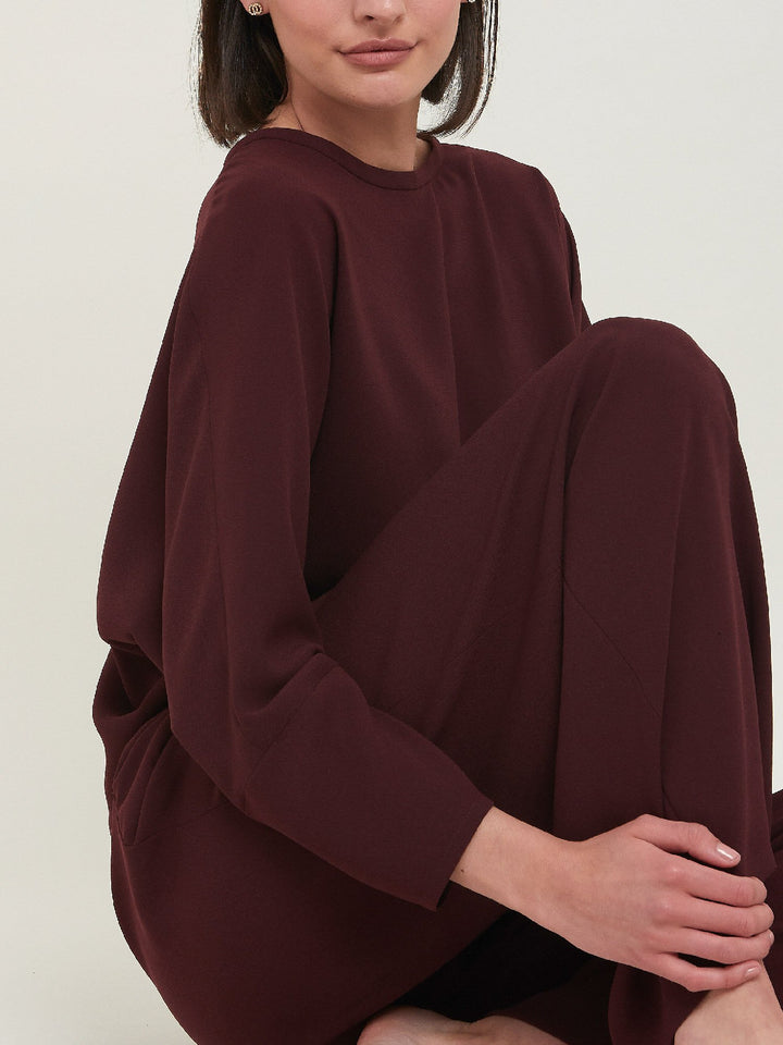 Lal, a crewneck relaxed fit sweatshirt. Crafted in a satin back crepe in rich burgundy. A sporty silhouette featuring an elasticated ribbed hem, dropped shoulder & full-length sleeve. Teams perfectly with matching Charlize pants. Clothes for how we live today! Loungewear re-defined. 