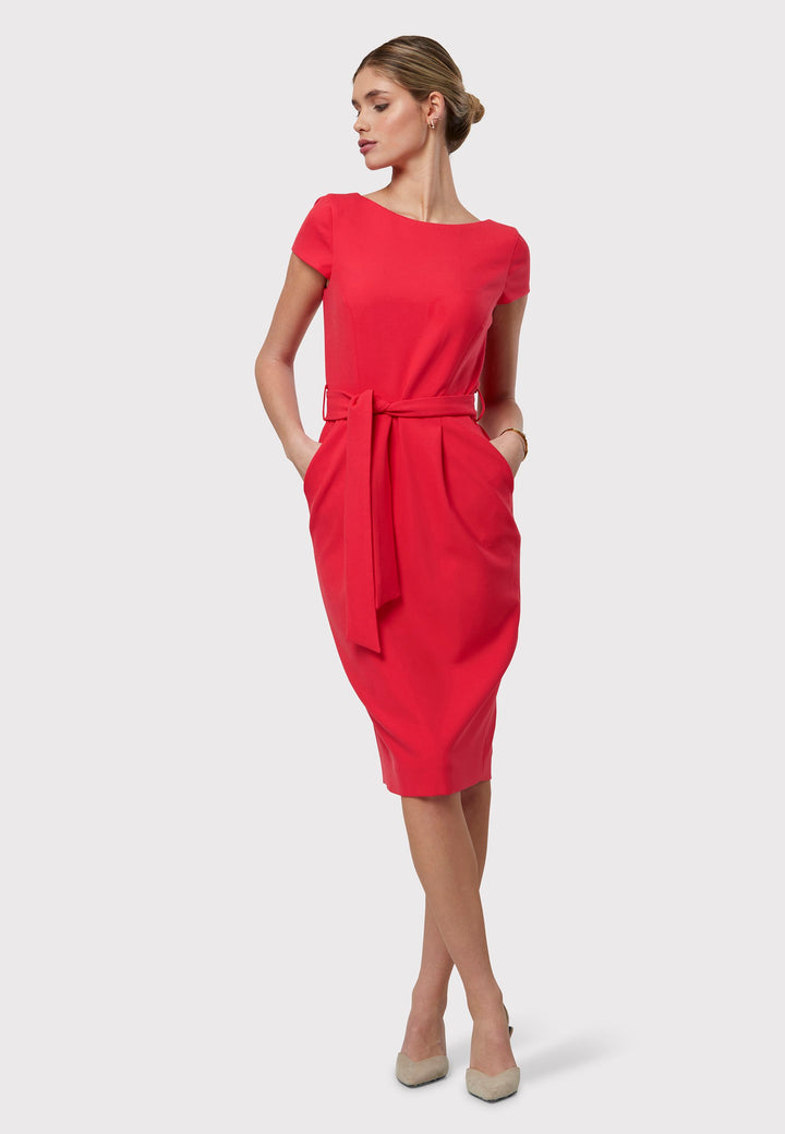 Layla, a capped-sleeve dress featuring a chic slash neck and pencil skirt silhouette. Designed with front tucks and side seam pockets for functionality, it comes with a detachable belt for versatile styling. Crafted from our signature tricotine with a touch of elastane, ensuring both comfort and effortless movement. Shown here in a striking begonia hue.