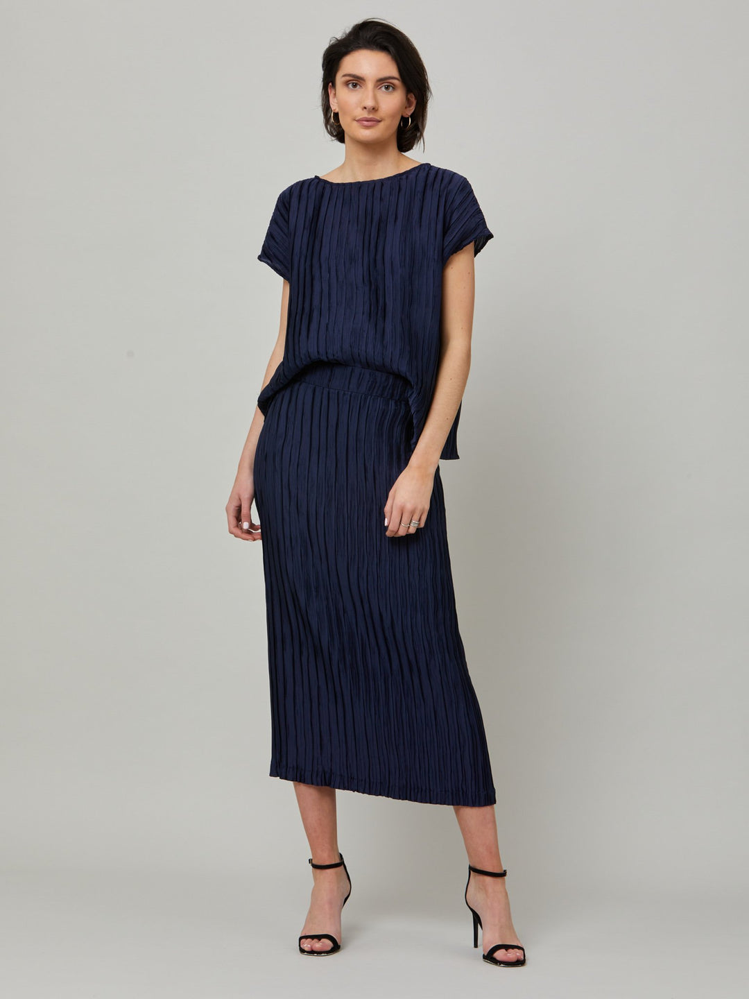 Lucy, our classic shell top is redefined in polished navy pleated fabric. A simple wardrobe essential, the perfect foil for the matching Roz navy pleated skirt.