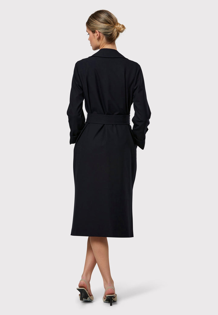 Lydiah is a timeless dark navy trench coat with a fluid design. Its detachable, row-stitched belt offers flexibility to cinch at the waist or wear it open for a relaxed style. Patch pockets combine both fashion and function, while the clean edge finish maintains a sleek, button-free look. Side slits add a contemporary touch and ensure ease of movement.