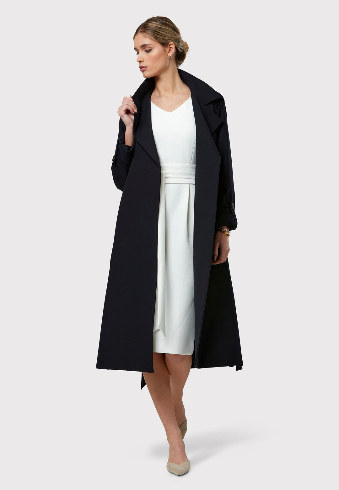 Lydiah is a timeless dark navy trench coat with a fluid design. Its detachable, row-stitched belt offers flexibility to cinch at the waist or wear it open for a relaxed style. Patch pockets combine both fashion and function, while the clean edge finish maintains a sleek, button-free look. Side slits add a contemporary touch and ensure ease of movement.