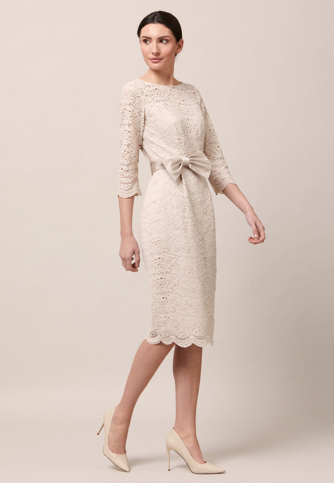 Turn Heads at your upcoming occasions in the Michelle dress. Crafted in an elegant lace dress in a warm oyster tone. This style fits close to the profile with a flattering finish. Engineered with pleats at the waistline to allow the fabric to fall softly over the hips. The satin bow-belt is detachable for added versatility. Features a scalloped hem and sleeves. Attending a summer wedding? Mother of the bride? Heading to the races? This is the dress for you. 