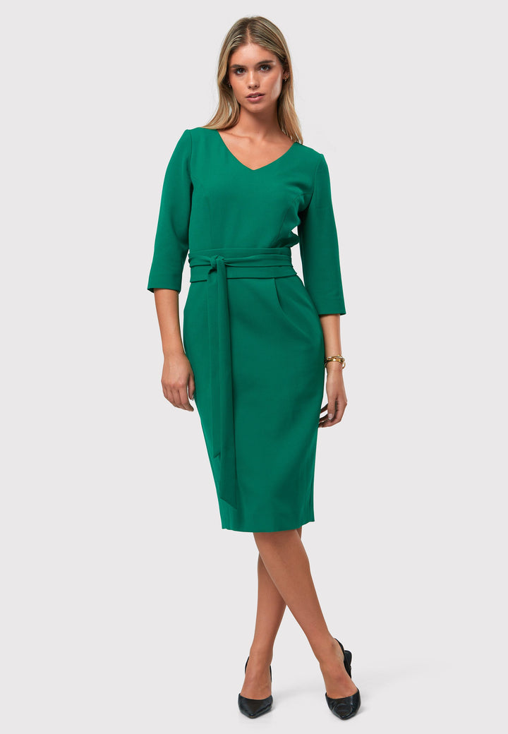 Introducing the Ophelia Dark Emerald Green Dress, a timeless and impeccably tailored silhouette. This expertly crafted dress features a form-flattering design with convenient pockets, a detachable belt, and a pencil skirt that falls to a chic mid-calf length. The sophisticated V-neckline adds an elegant touch to the overall look. Crafted from sustainably sourced fibers with a hint of stretch, this dress ensures both comfort and ease of movement. 