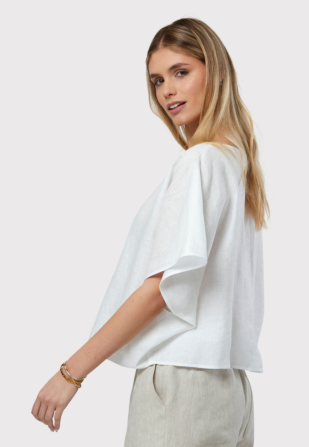 Quinn White Linen Shirt offers an effortless warm-weather look, crafted from breathable pure linen with a flattering v-neck design. Its easy fit ensures summer comfort, complemented by subtle pleat detailing on the back hem for added style.