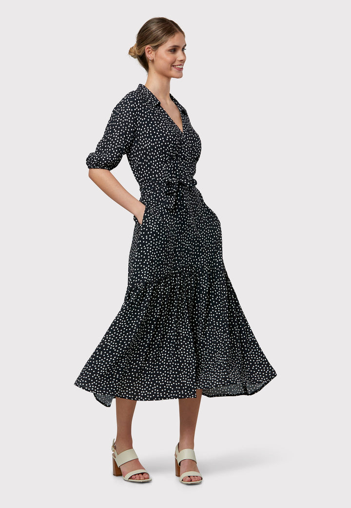 Raquel channels 30's glamour with its classic navy and white polka dot design in our favored viscose crepe. This dress boasts a flattering fit-and-flare skirt and a cross-over V-neckline. A soft belt cinches the waist, offering a customizable look that enhances the figure—whether tied at the front or back, the belt provides styling versatility. Elbow-length sleeves complete the 30's-inspired silhouette, making it a versatile wardrobe essential.