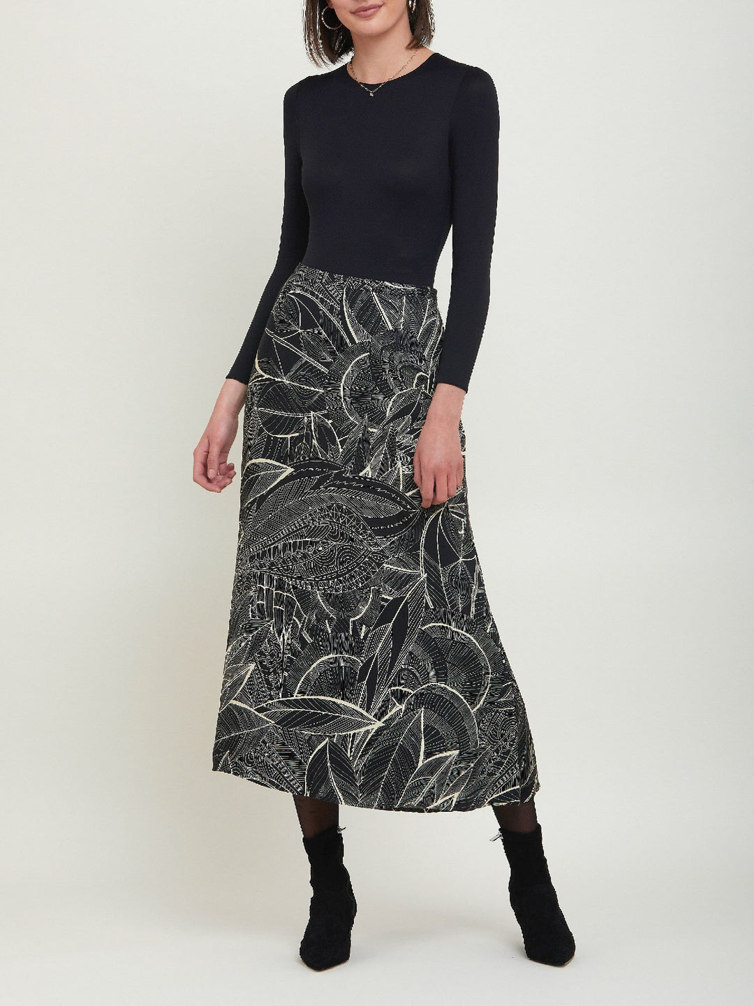 Riley, a simple slip skirt. Crafted in a fluid viscose fabric in an abstract botanical cream on black print. This Hip skimming silhouette flares below the knee & falls to the mid-calf. Helen proposes to style with a cozy sweater or dress up with a timeless black body.