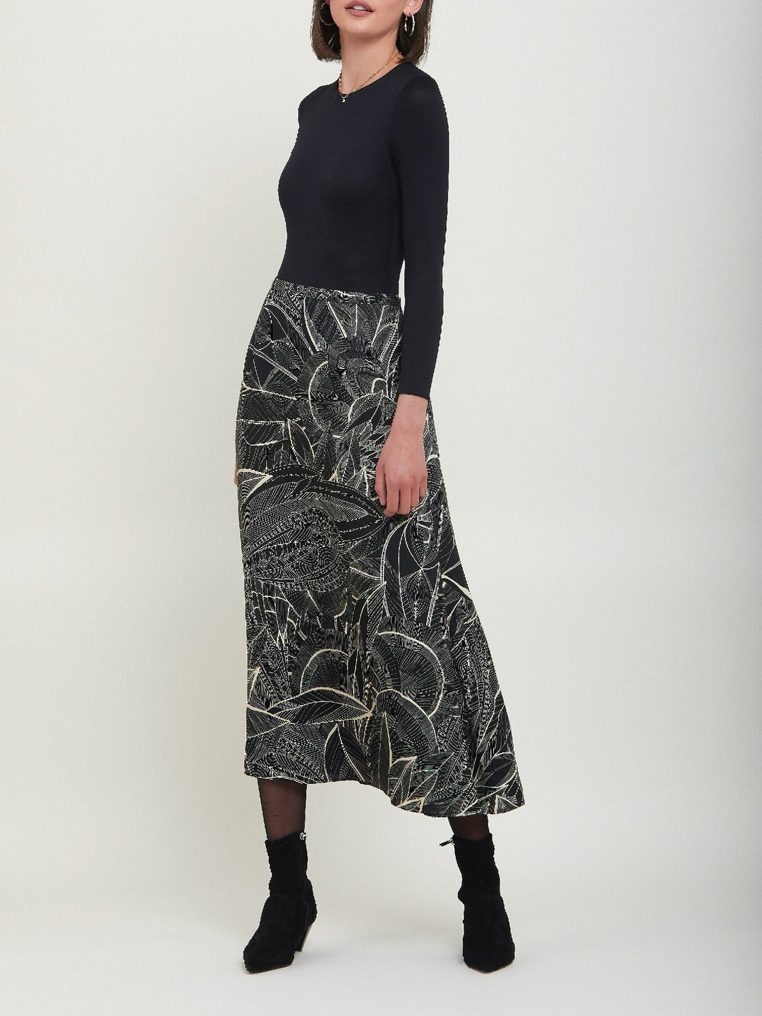 Riley, a simple slip skirt. Crafted in a fluid viscose fabric in an abstract botanical cream on black print. This Hip skimming silhouette flares below the knee & falls to the mid-calf. Helen proposes to style with a cozy sweater or dress up with a timeless black body.