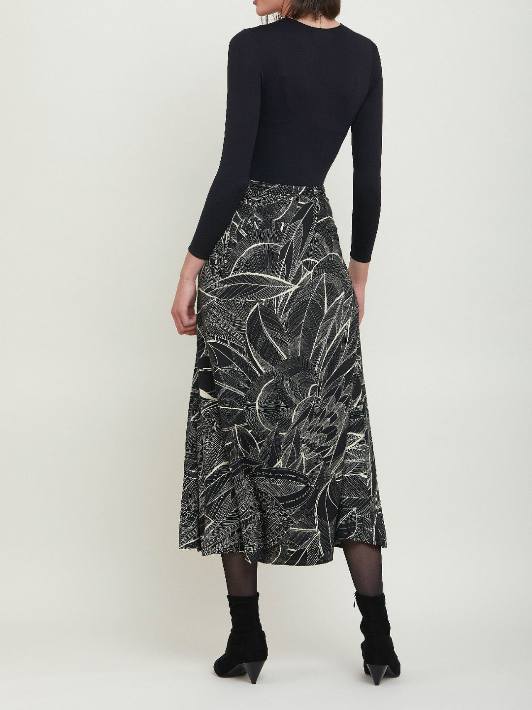 Riley, a simple slip skirt. Crafted in a fluid viscose fabric in an abstract botanical cream on black print. This Hip skimming silhouette flares below the knee & falls to the mid-calf. Helen proposes to style with a cozy sweater or dress up with a timeless black body.
