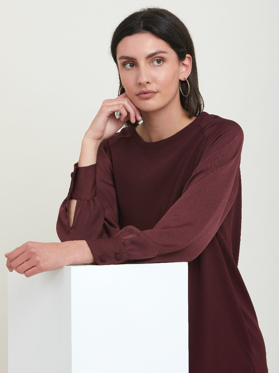 Sarah, a simple easy-fit shift dress. Crafted in a satin back crepe in rich burgundy. Features a satin raglan sleeve & a deep satin band at the hem which adds elegance to this versatile piece. Offers handy side seam pockets for added comfort and functionality. A fresh take on occasion wear.