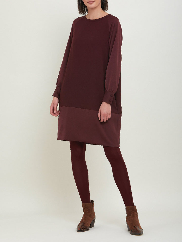 Sarah, a simple easy-fit shift dress. Crafted in a satin back crepe in rich burgundy. Features a satin raglan sleeve & a deep satin band at the hem which adds elegance to this versatile piece. Offers handy side seam pockets for added comfort and functionality. A fresh take on occasion wear.
