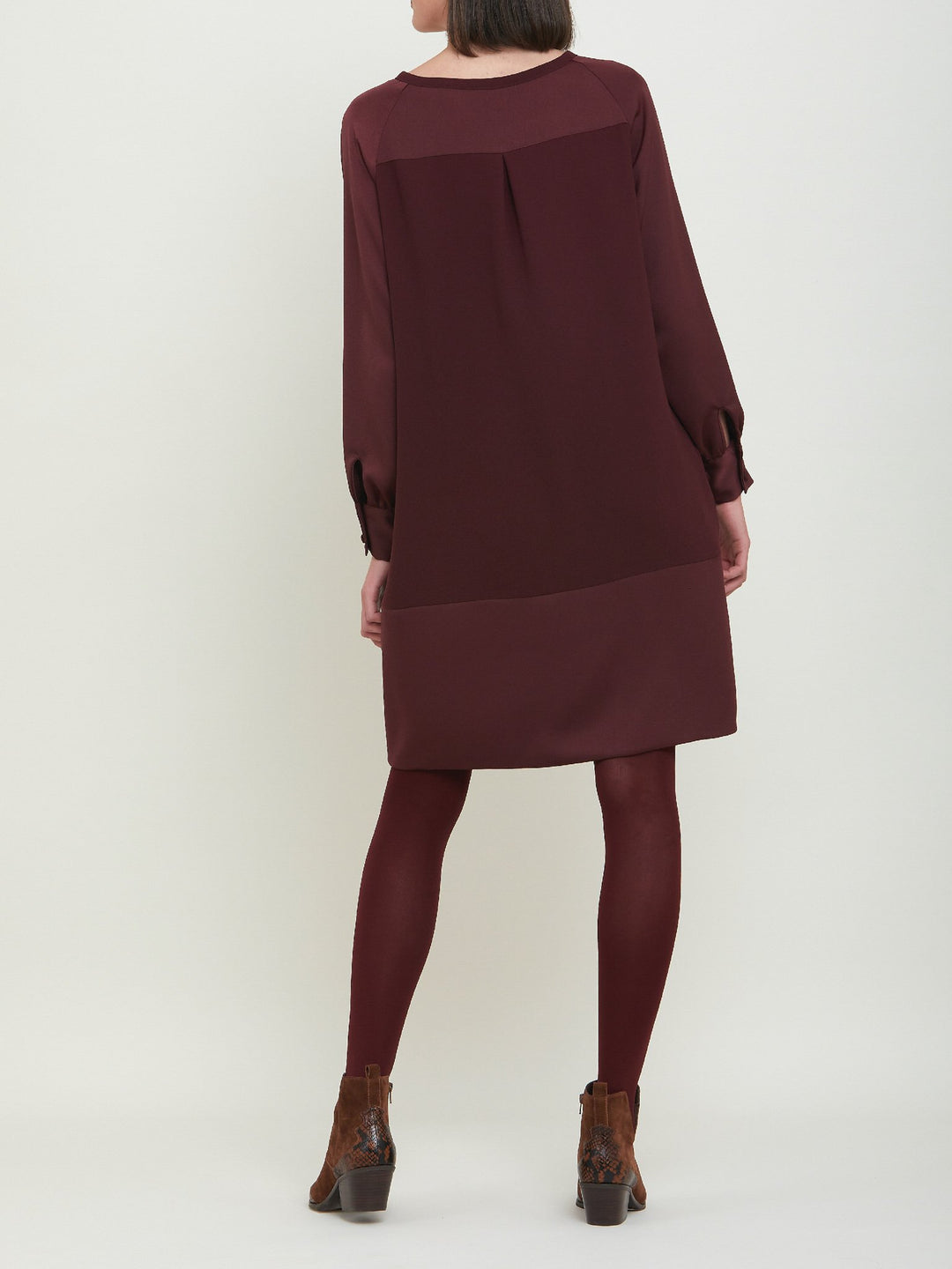 Sarah, a simple easy-fit shift dress. Crafted in a satin back crepe in rich burgundy. Features a satin raglan sleeve & a deep satin band at the hem which adds elegance to this versatile piece. Offers handy side seam pockets for added comfort and functionality. A fresh take on occasion wear.