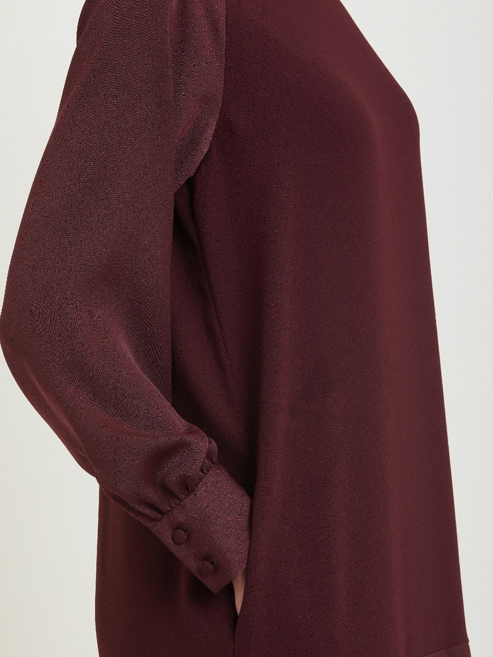 Sarah, a simple easy-fit shift dress. Crafted in a satin back crepe in rich burgundy. Features a satin raglan sleeve & a deep satin band at the hem which adds elegance to this versatile piece. Offers handy side seam pockets for added comfort and functionality. A fresh take on occasion wear.