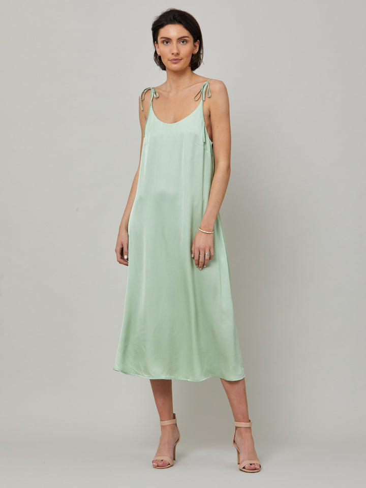 The Ultimate slip dress. Classic occasion wear, modernized.  Meet the Sonica dress in luxurious tea green satin viscose. An easy-fitting slip dress that falls to the mid-calf. Features adjustable tie straps at the shoulder and an elegant plunging back detail.  . Attending a summer wedding? Mother of the bride? Heading to the races? This is the dress for you. Designed in Ireland by Helen McAlinden. Made in Europe. Free shipping to the EU & UK.