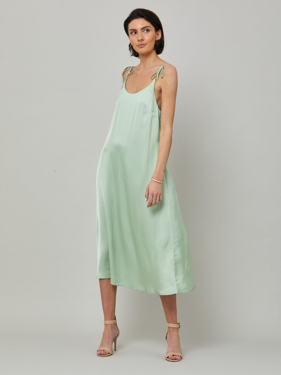 The Ultimate slip dress. Classic occasion wear, modernized.  Meet the Sonica dress in luxurious tea green satin viscose. An easy-fitting slip dress that falls to the mid-calf. Features adjustable tie straps at the shoulder and an elegant plunging back detail.  . Attending a summer wedding? Mother of the bride? Heading to the races? This is the dress for you. Designed in Ireland by Helen McAlinden. Made in Europe. Free shipping to the EU & UK.