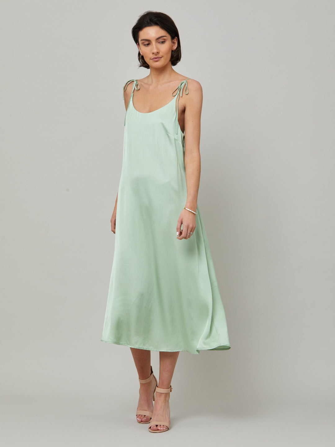 The Ultimate slip dress. Classic occasion wear, modernized.  Meet the Sonica dress in luxurious tea green satin viscose. An easy-fitting slip dress that falls to the mid-calf. Features adjustable tie straps at the shoulder and an elegant plunging back detail.  . Attending a summer wedding? Mother of the bride? Heading to the races? This is the dress for you. Designed in Ireland by Helen McAlinden. Made in Europe. Free shipping to the EU & UK.
