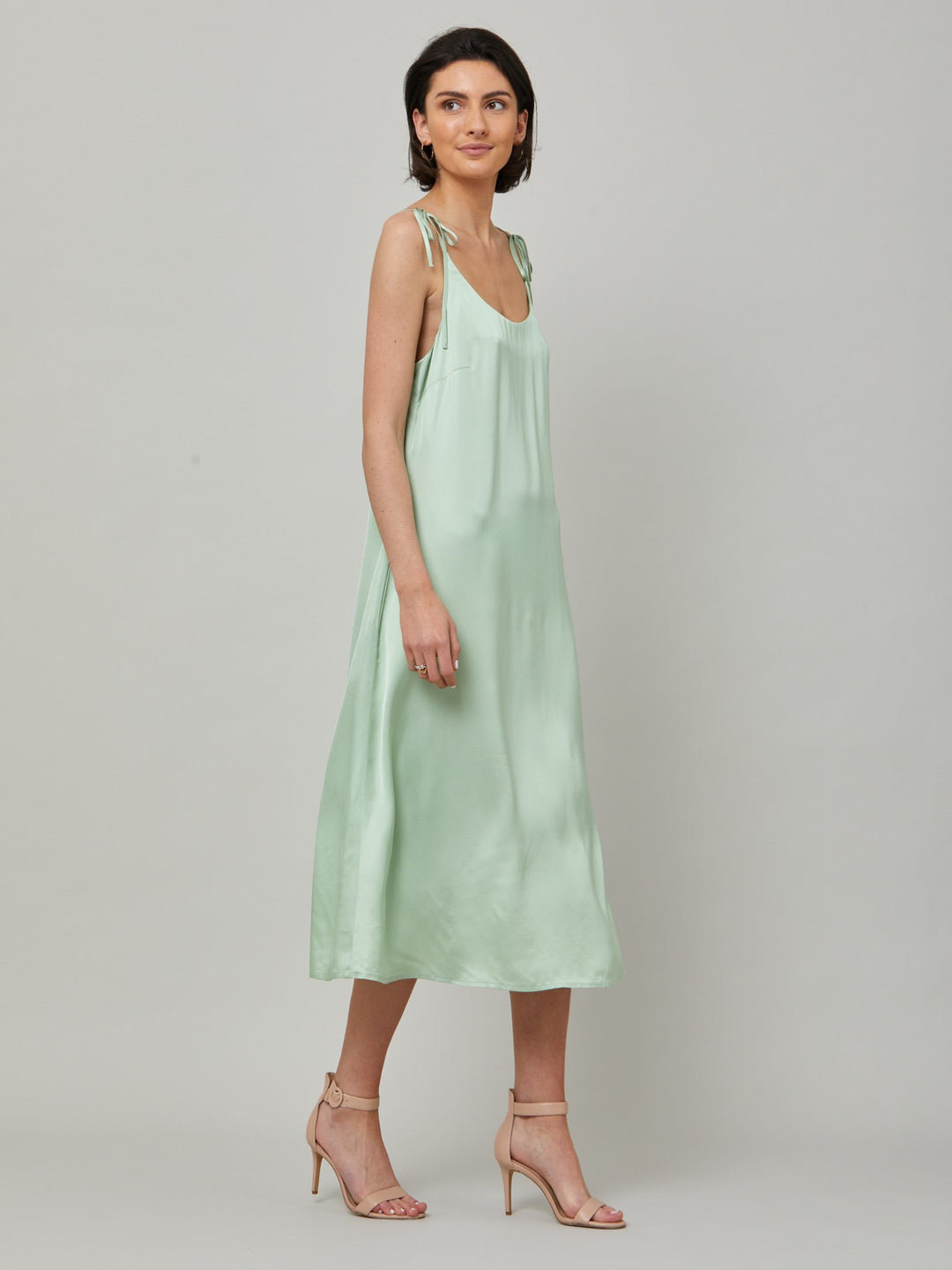 The Ultimate slip dress. Classic occasion wear, modernized.  Meet the Sonica dress in luxurious tea green satin viscose. An easy-fitting slip dress that falls to the mid-calf. Features adjustable tie straps at the shoulder and an elegant plunging back detail.  . Attending a summer wedding? Mother of the bride? Heading to the races? This is the dress for you. Designed in Ireland by Helen McAlinden. Made in Europe. Free shipping to the EU & UK.