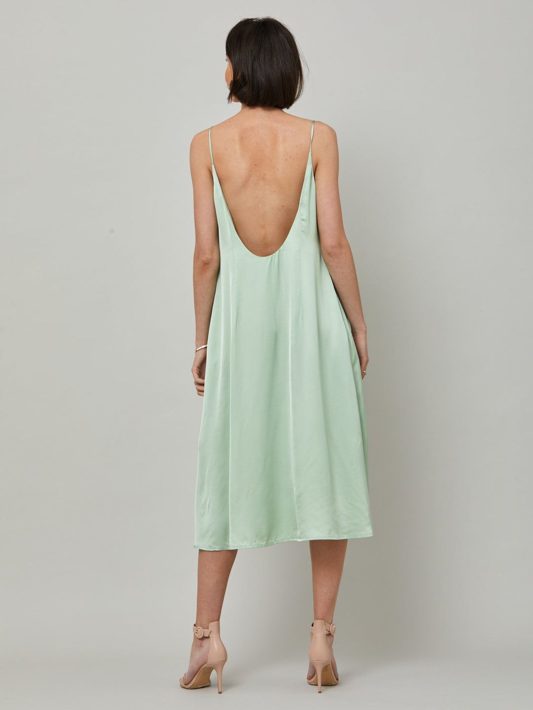 The Ultimate slip dress. Classic occasion wear, modernized.  Meet the Sonica dress in luxurious tea green satin viscose. An easy-fitting slip dress that falls to the mid-calf. Features adjustable tie straps at the shoulder and an elegant plunging back detail.  . Attending a summer wedding? Mother of the bride? Heading to the races? This is the dress for you. Designed in Ireland by Helen McAlinden. Made in Europe. Free shipping to the EU & UK.