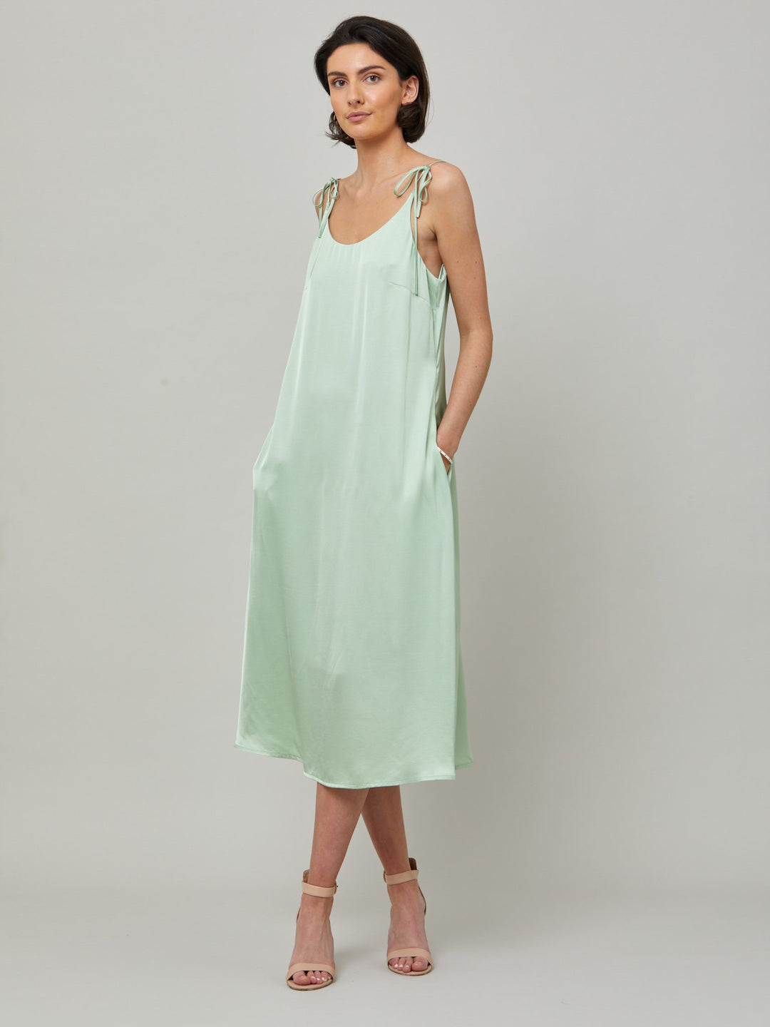 The Ultimate slip dress. Classic occasion wear, modernized.  Meet the Sonica dress in luxurious tea green satin viscose. An easy-fitting slip dress that falls to the mid-calf. Features adjustable tie straps at the shoulder and an elegant plunging back detail.  . Attending a summer wedding? Mother of the bride? Heading to the races? This is the dress for you. Designed in Ireland by Helen McAlinden. Made in Europe. Free shipping to the EU & UK.