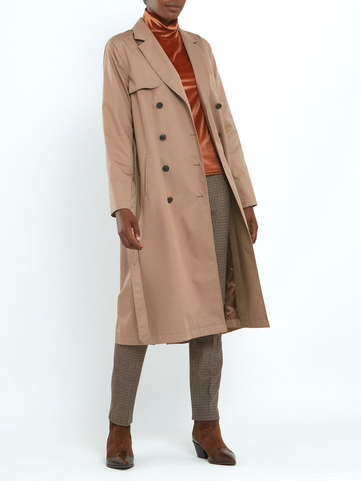 Camel trench coat double-breasted, classic collar and revere, gun flap, back vent, jetted pockets, and buckle belt. Fabricated in shower-resistant cotton poplin