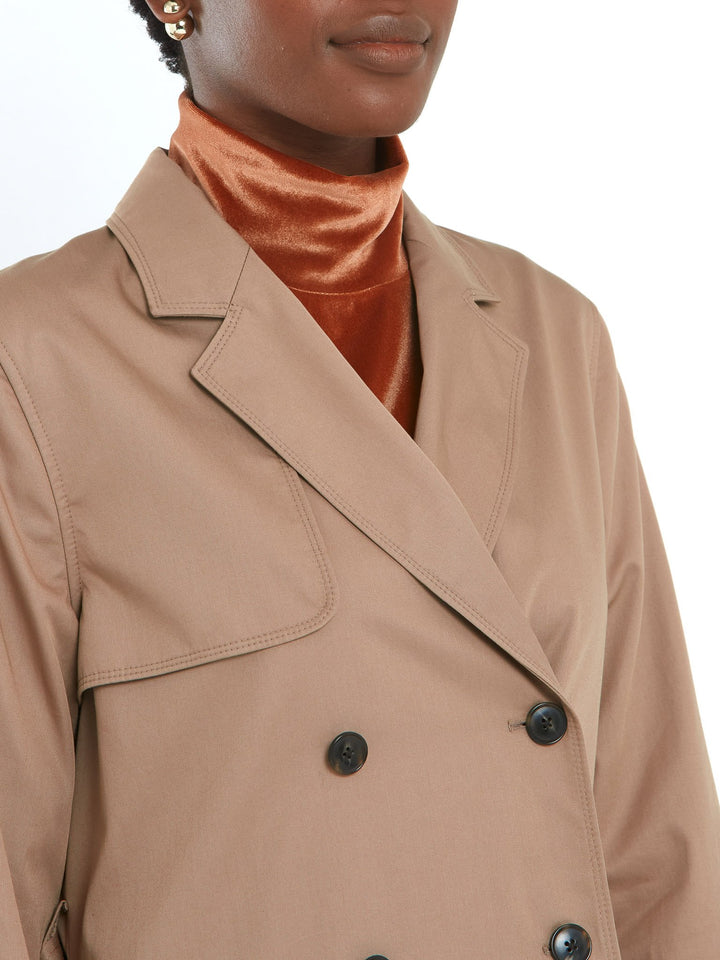 Camel trench coat double-breasted, classic collar and revere, gun flap, back vent, jetted pockets, and buckle belt. Fabricated in shower-resistant cotton poplin