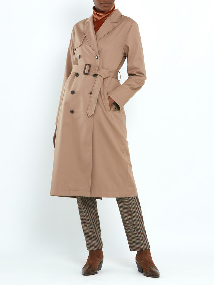 Camel trench coat double-breasted, classic collar and revere, gun flap, back vent, jetted pockets, and buckle belt. Fabricated in shower-resistant cotton poplin