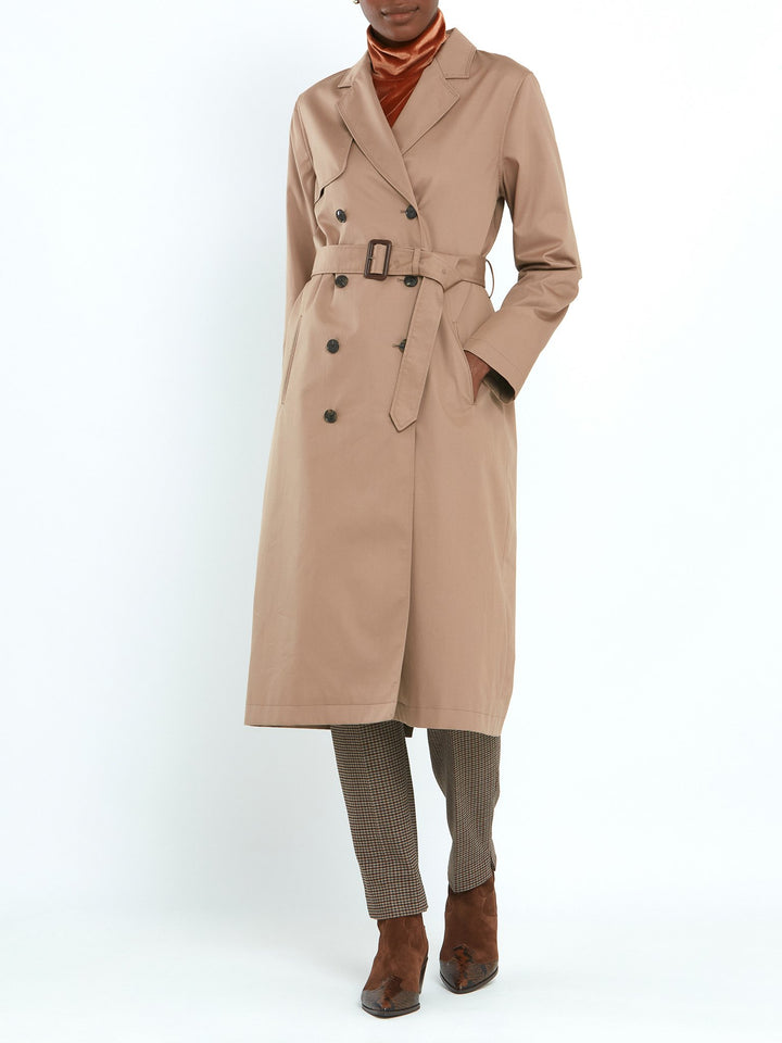 Camel trench coat double-breasted, classic collar and revere, gun flap, back vent, jetted pockets, and buckle belt. Fabricated in shower-resistant cotton poplin