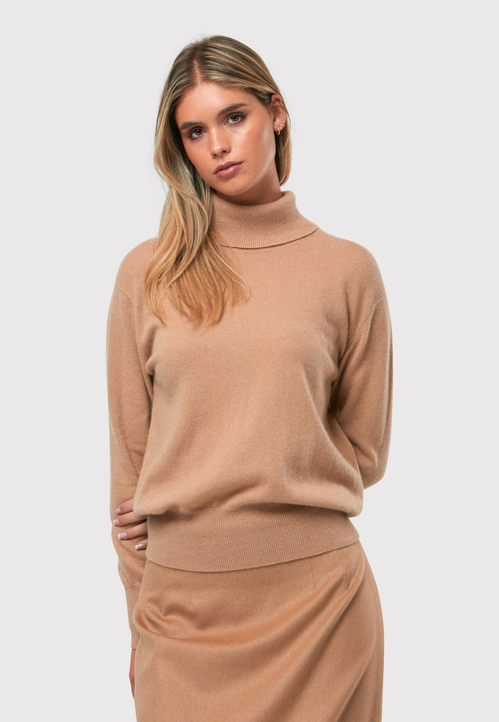 Introducing the Theresa Camel Cashmere Jumper, a luxurious and timeless wardrobe staple. This jumper features a tight roll-down polo neck, exuding sophistication and warmth. With full-length sleeves and tight ribbed cuffs and hem, it offers a comfortable and flattering fit. Crafted from soft and cozy cashmere, this jumper combines elegance and comfort effortlessly.