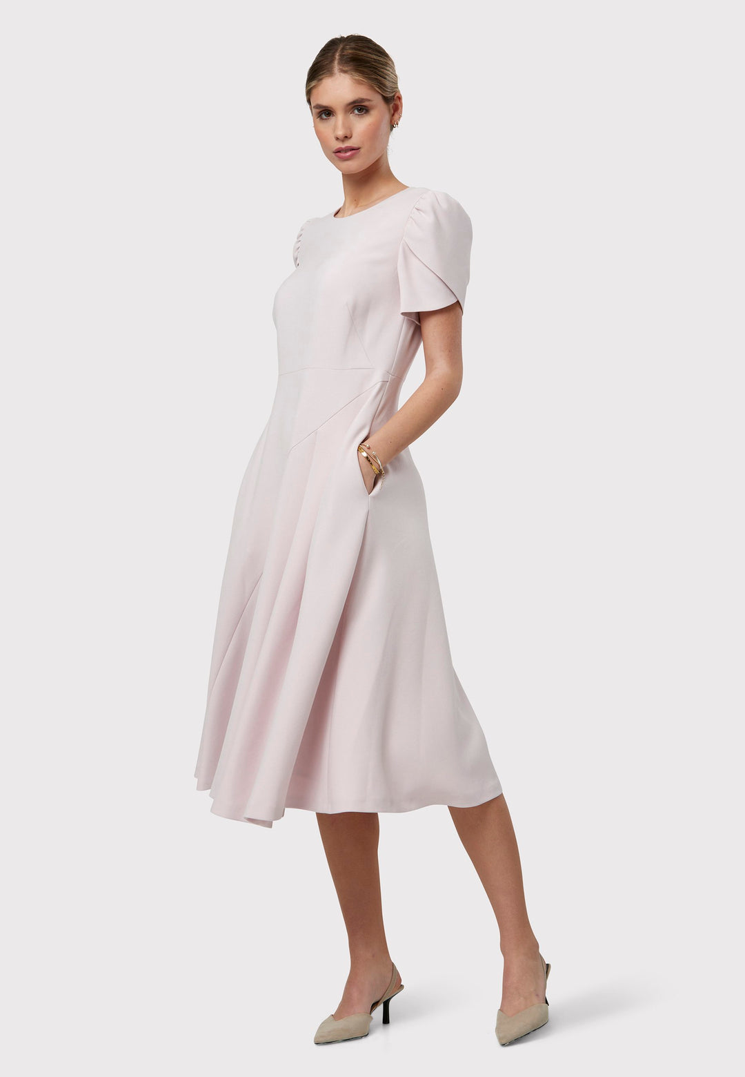 The Vera Soft Pink Dress is a captivating fit-and-flare piece. This feminine round-neck dress showcases a flared skirt that falls to a flattering mid-calf length, complete with practical pockets. The sleeves are adorned with intricate overlapping details, adding a unique touch of interest.