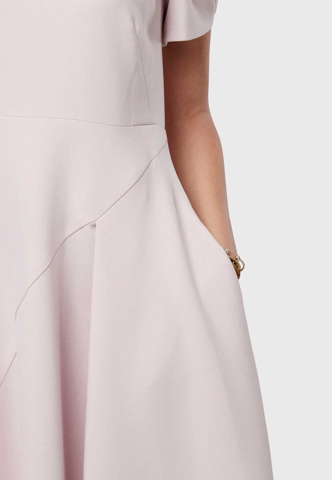 The Vera Soft Pink Dress is a captivating fit-and-flare piece. This feminine round-neck dress showcases a flared skirt that falls to a flattering mid-calf length, complete with practical pockets. The sleeves are adorned with intricate overlapping details, adding a unique touch of interest.