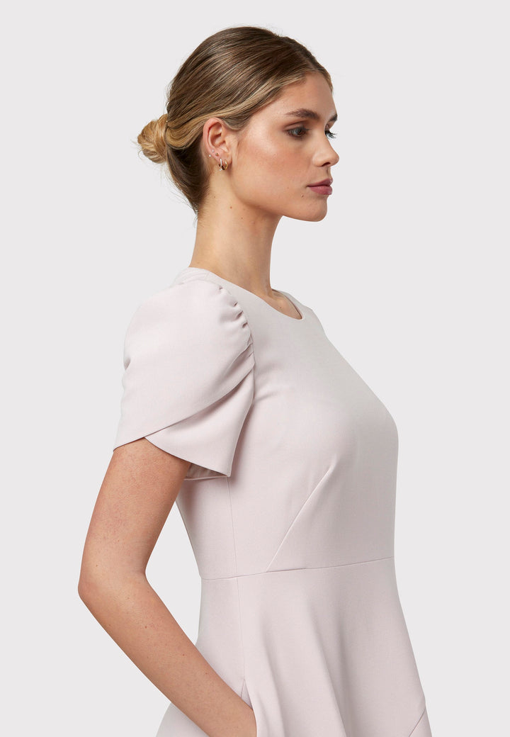 The Vera Soft Pink Dress is a captivating fit-and-flare piece. This feminine round-neck dress showcases a flared skirt that falls to a flattering mid-calf length, complete with practical pockets. The sleeves are adorned with intricate overlapping details, adding a unique touch of interest.