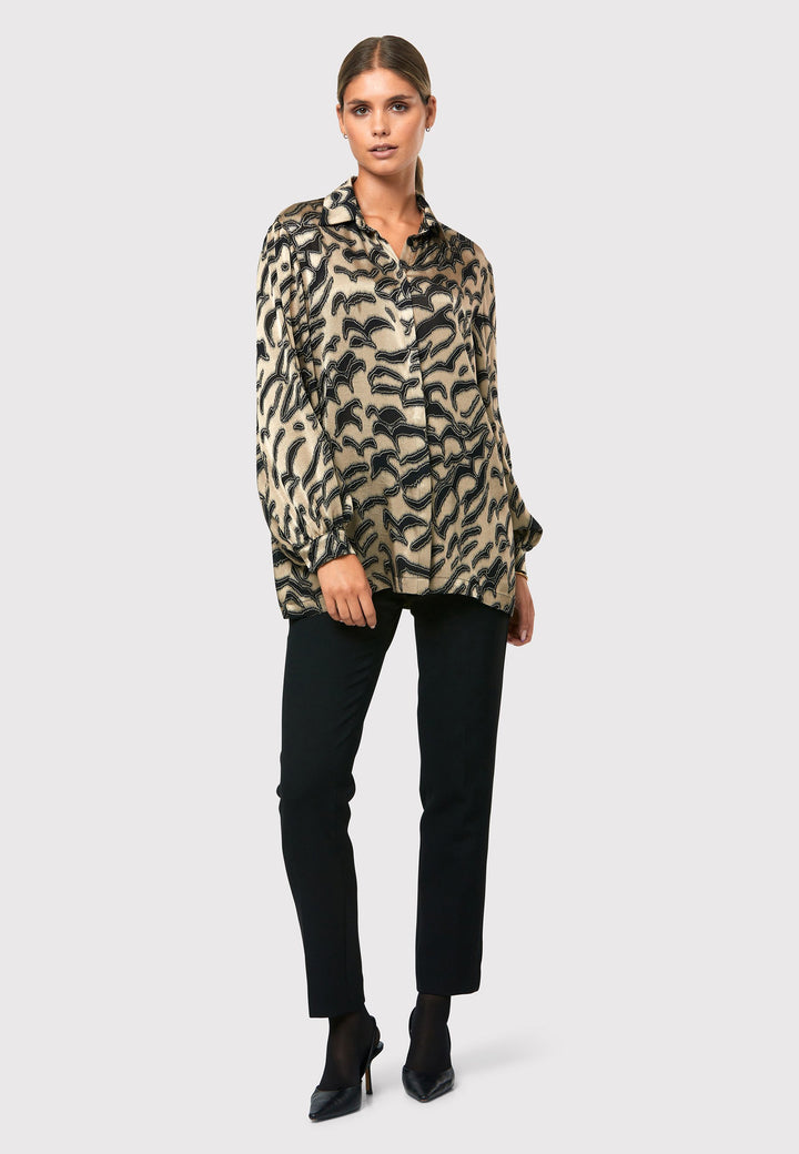 Introducing the Viola Devore Shirt, a stunning and luxurious piece that will make a statement in your wardrobe. This shirt features a captivating gold satin fabric adorned with black abstract details, creating a visually striking design. The voluminous sleeves elegantly flow into a tight buttoned cuff, adding a touch of sophistication. With its slightly dropped shoulders, this shirt offers a relaxed yet stylish fit. 
