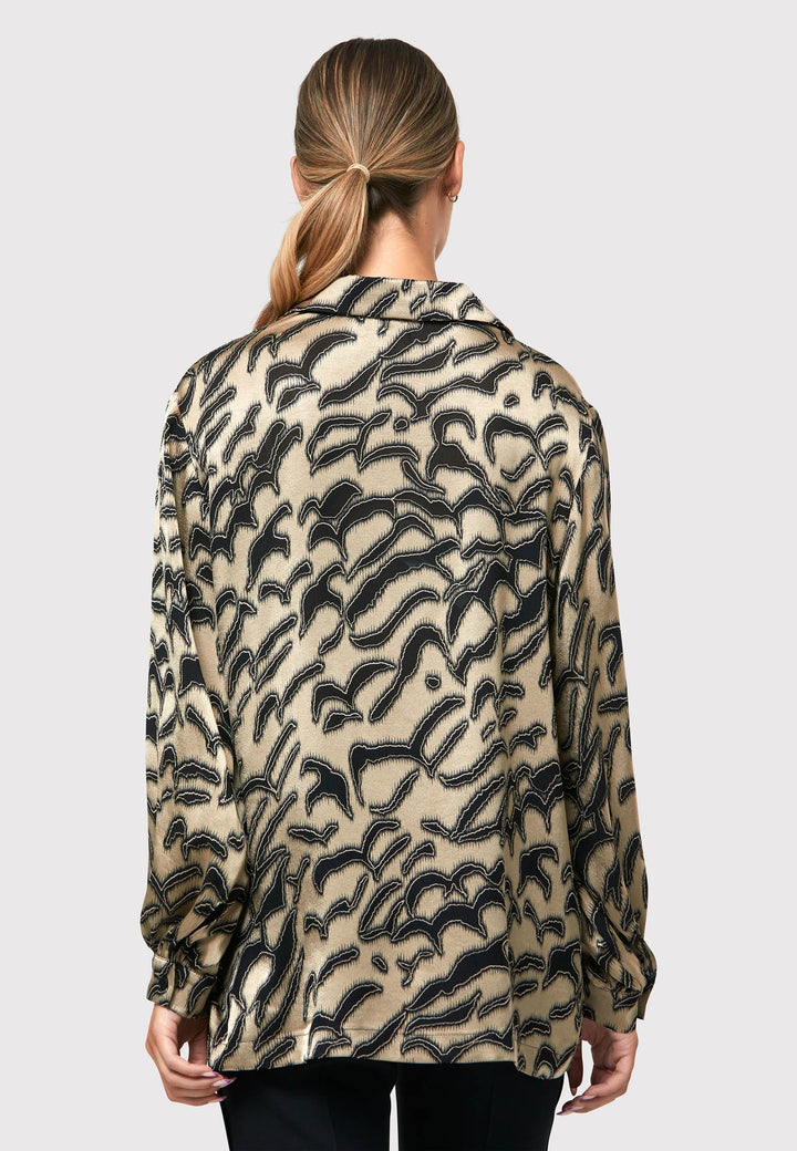 Introducing the Viola Devore Shirt, a stunning and luxurious piece that will make a statement in your wardrobe. This shirt features a captivating gold satin fabric adorned with black abstract details, creating a visually striking design. The voluminous sleeves elegantly flow into a tight buttoned cuff, adding a touch of sophistication. With its slightly dropped shoulders, this shirt offers a relaxed yet stylish fit. 
